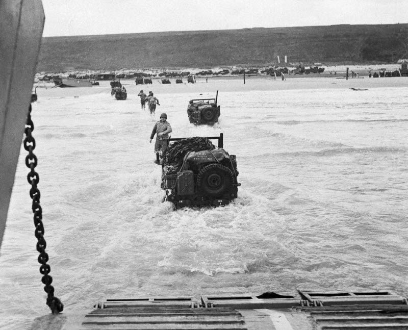 American troops and jeeps go ashore from landing craft at Normandy