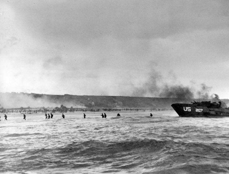 American infantrymen wade ashore at Normandy under naval shellfire